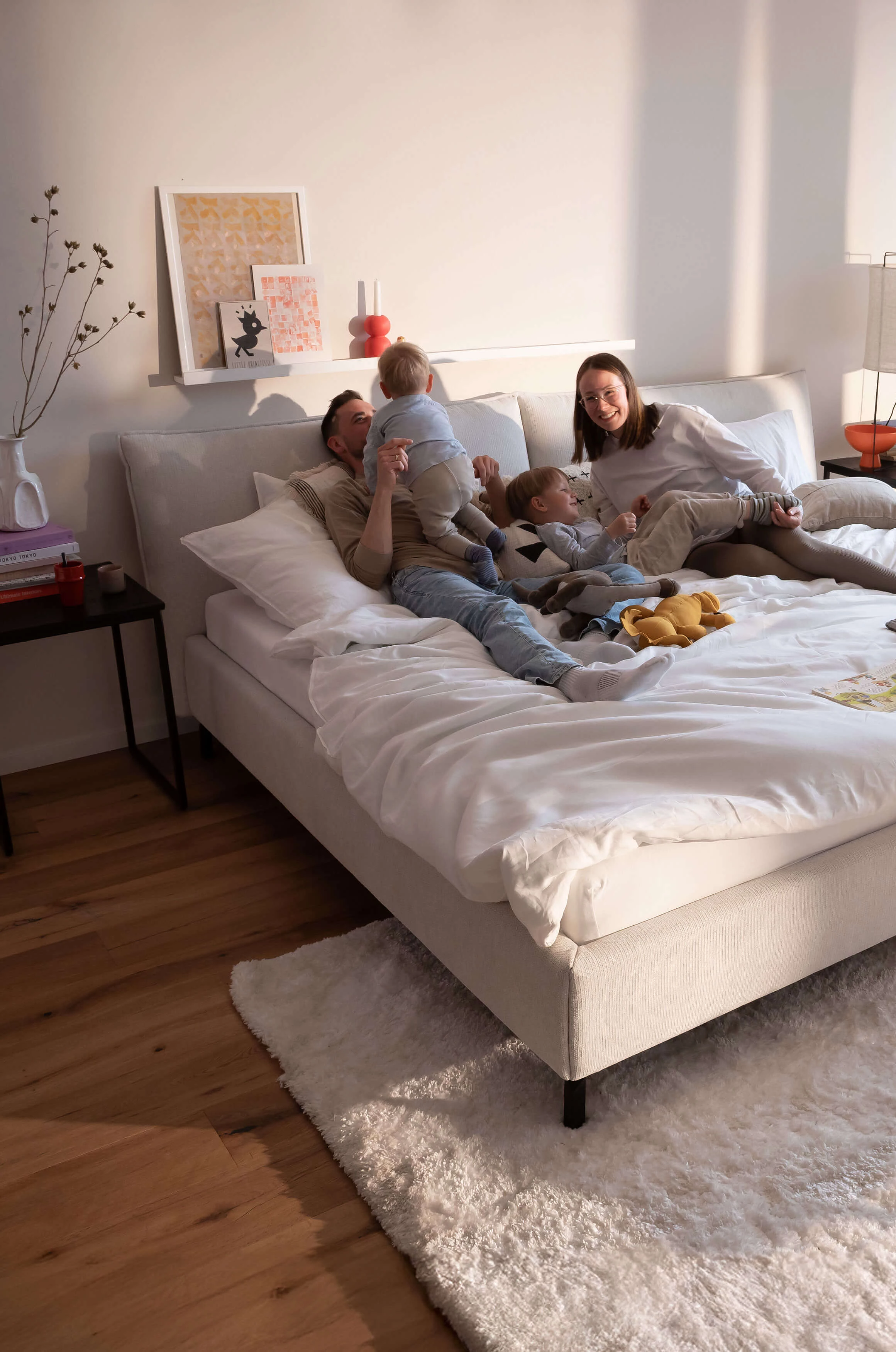 Familie auf einem Familienbett in Bezug Famous in der Farbe Snow im wohnlichen Ambiente