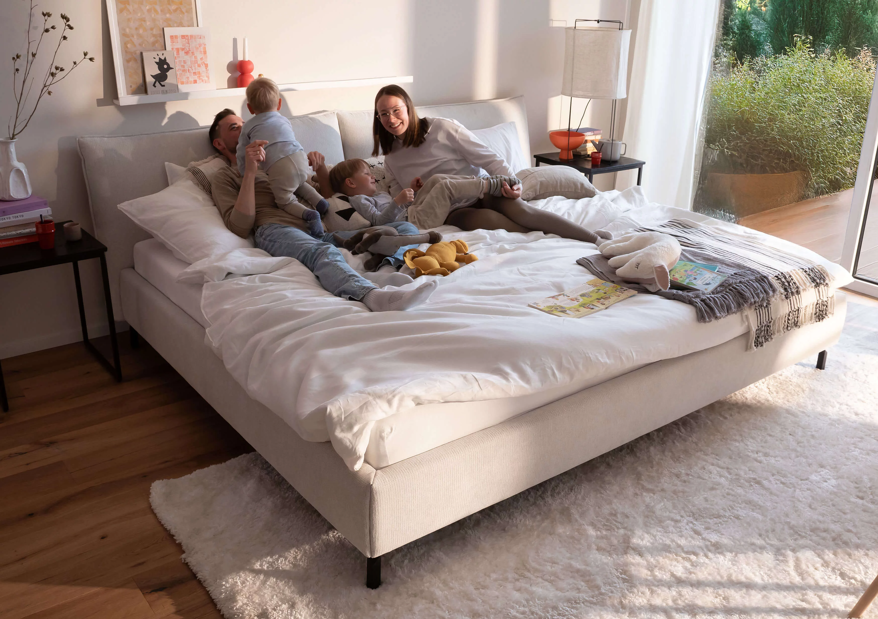 Familie auf einem Familienbett in Bezug Famous in der Farbe Snow im wohnlichen Ambiente