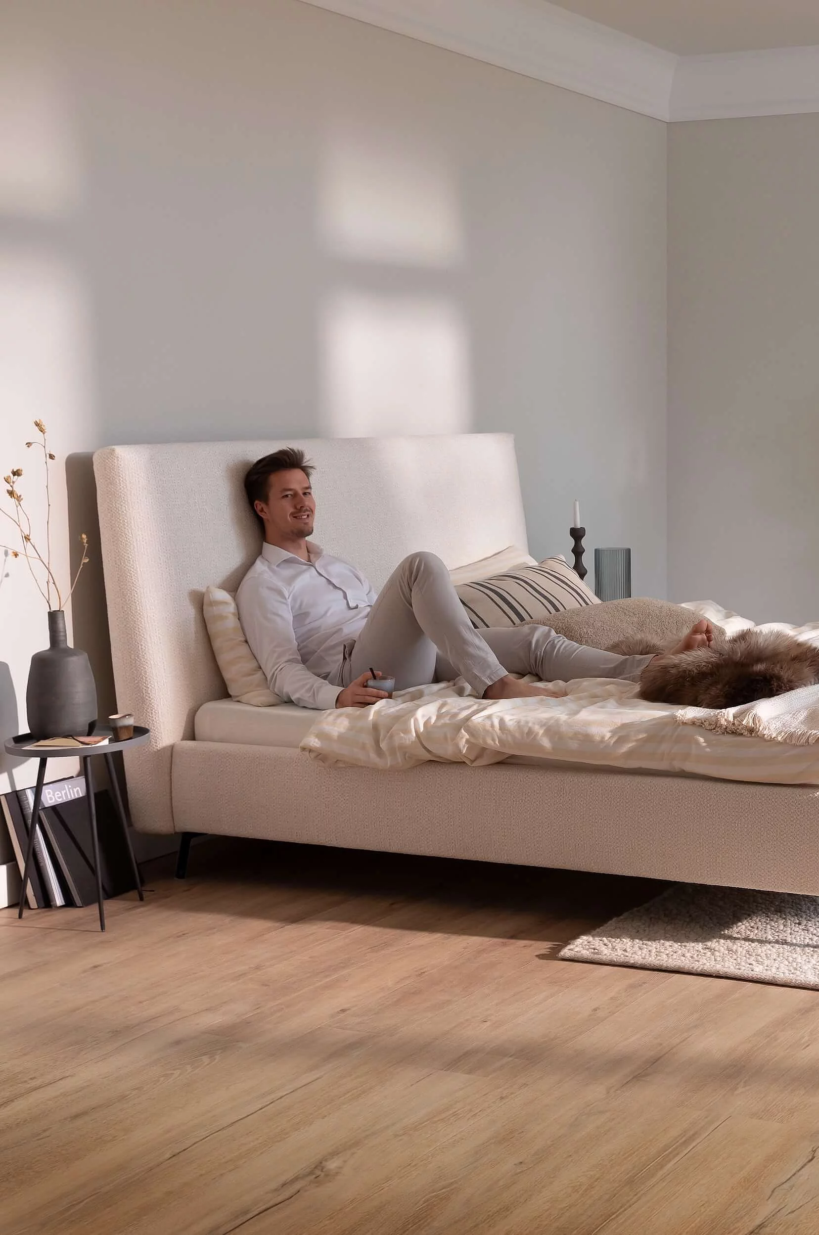 A double bed with a white duvet cover, a high headboard and slender black metal legs, set against a cosy backdrop