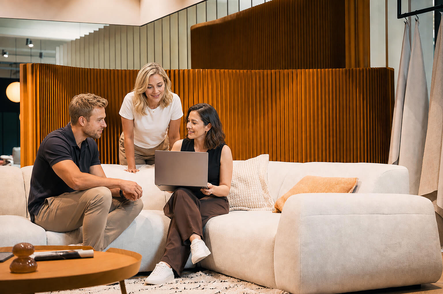 Drei Personen sitzen auf einem hellen Ecksofa im Showroom