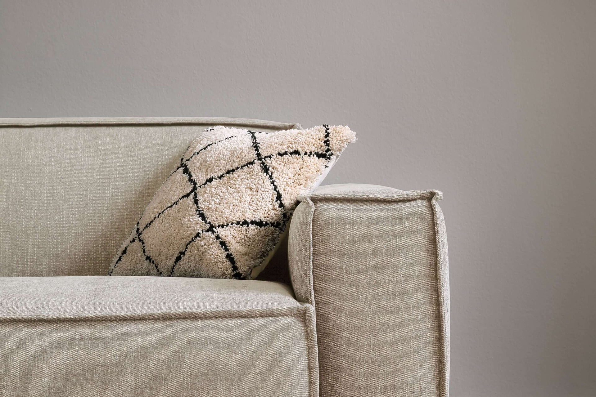 A close-up of the armrest of the Upper East single sofa, upholstered in Yelda fabric in the colour Nature