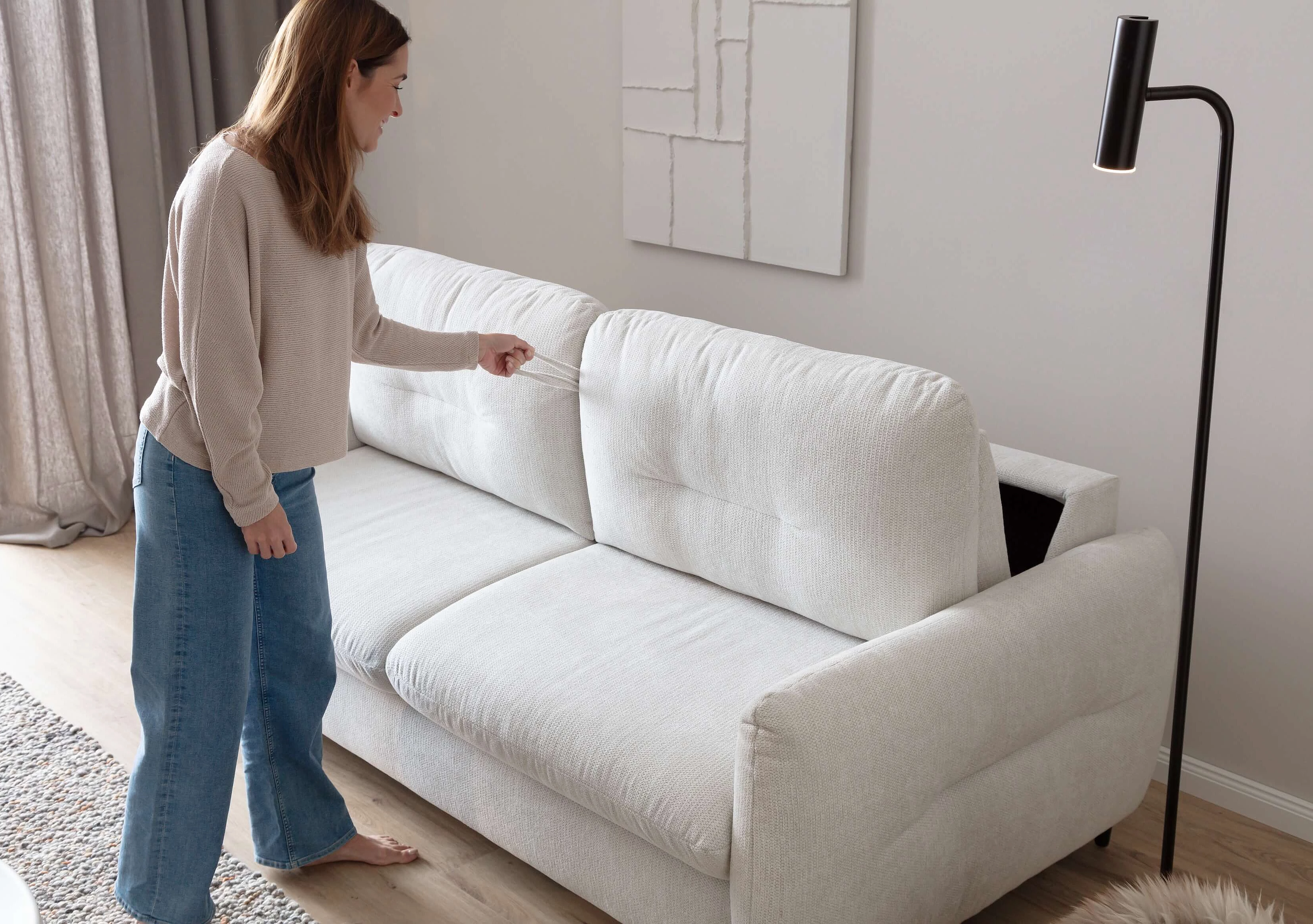 Schlafsofa Cassie in Bezug Famous in der Farbe Snow beim Aufziehen der Schlaffunktion in Wohnambiente